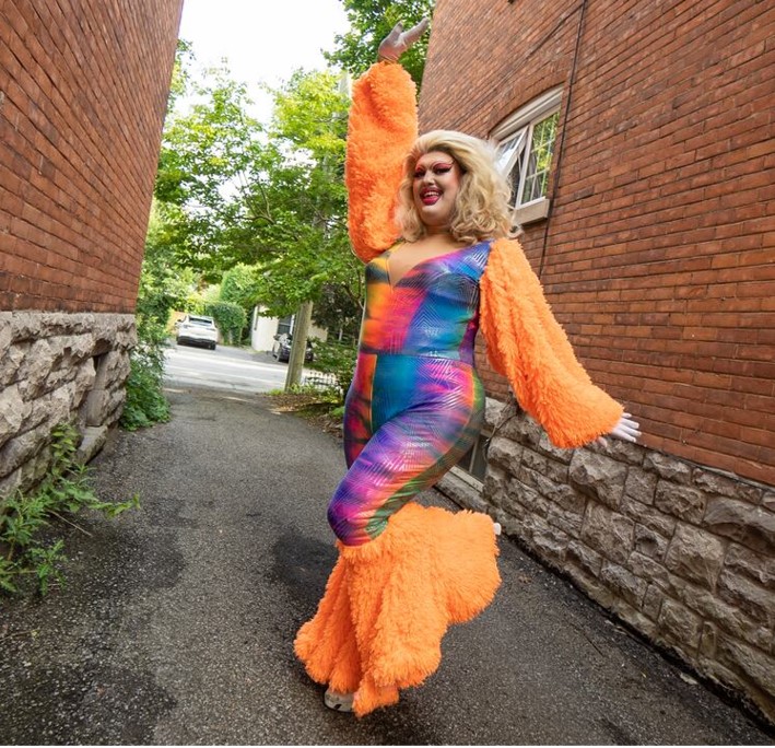 Holli Cow drag queen posing in between two brick buildings